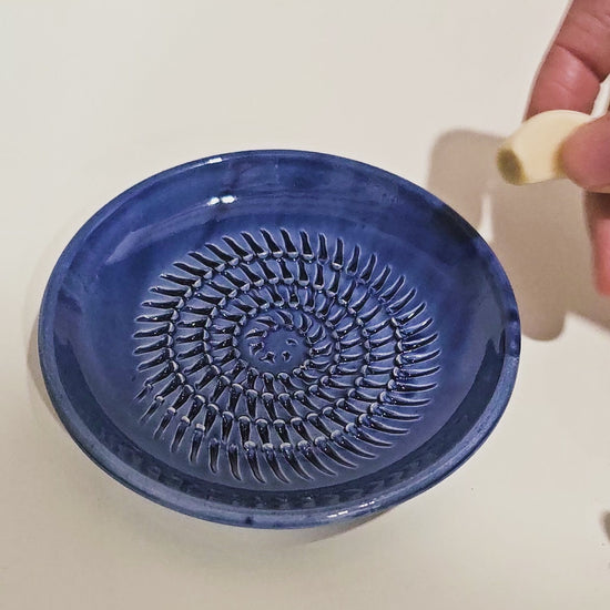 Garlic clover being grated on grate plate