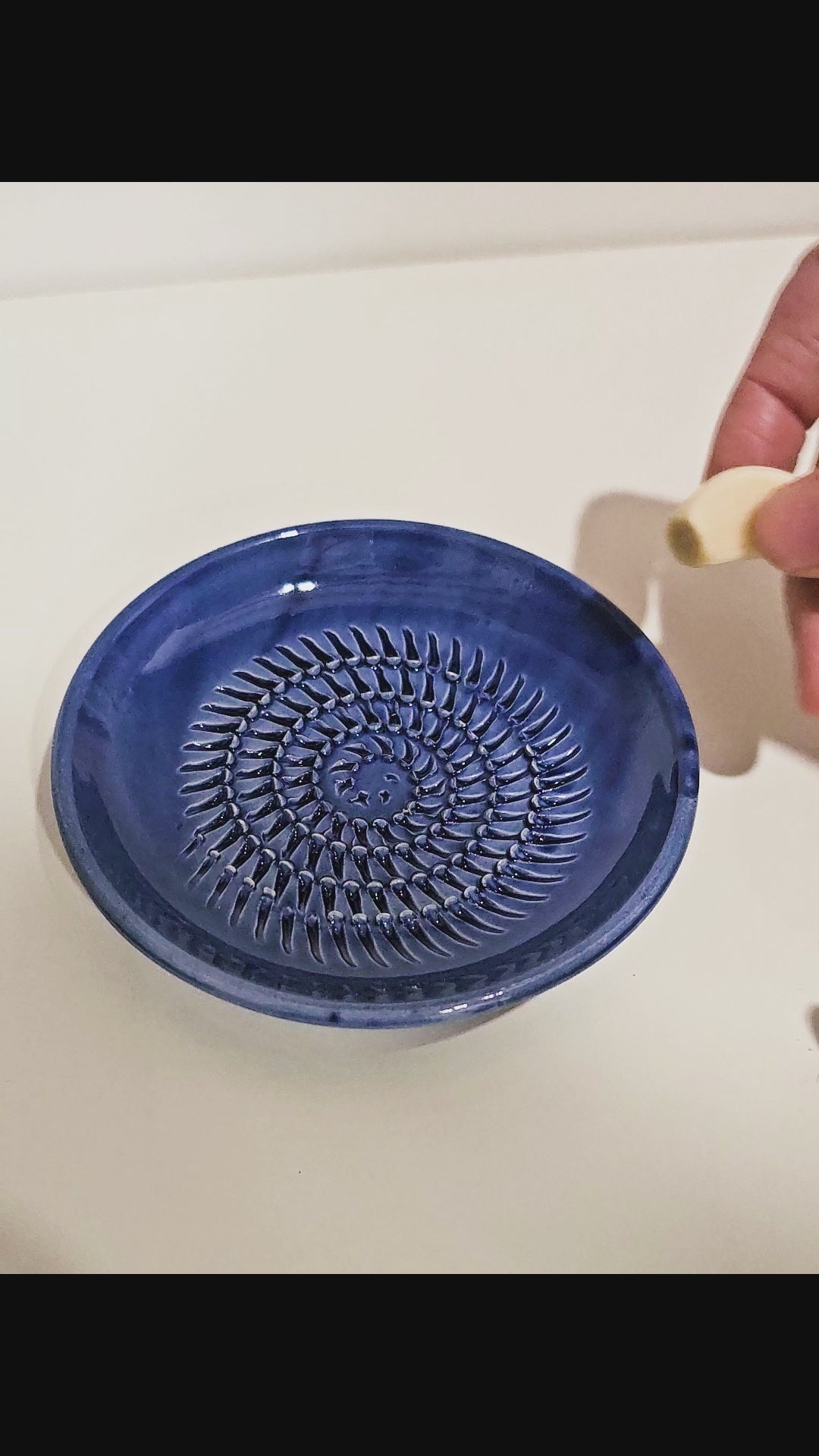 Garlic clover being grated on grate plate